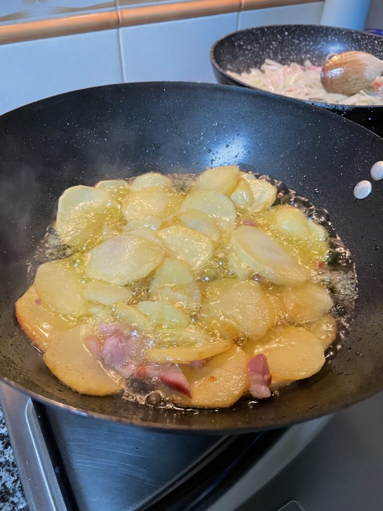batatas às rodelas a fritar em azeite e bacon